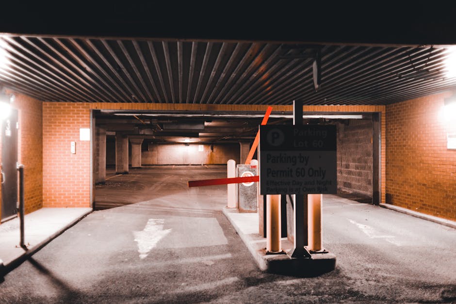 A blue and white parking sign with a wheelchair symbol indicating accessible parking is mounted on a metal post, positioned against a dark grey textured wall. The sign is illuminated by natural daylight, casting a faint shadow on the wall behind it. The surrounding area appears to be an outdoor parking space, possibly near a building entrance. In the context of home relocation and moving services offered by Man with Van Old Oak Common, this parking sign signifies designated accessible parking for vehicles involved in furniture transport, packing and moving, or loading processes, ensuring convenient access for moving activities near Wormwood Scrubs and Old Oak Common. The image emphasizes parking arrangements essential for efficient and accessible house removals or removals involving special access considerations.